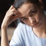 A woman looking annoyed while her head rests on her fist