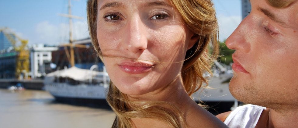 A women looking slightly away from a guy that wants to hug her.