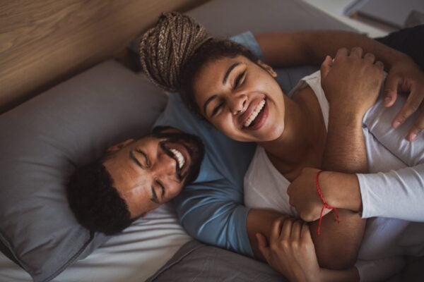 A woman and a man happily cuddling in bed