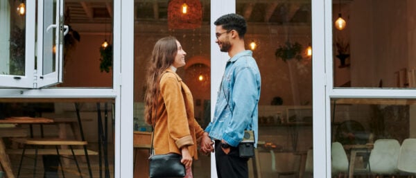 A man and a woman are standing in front of the windows looking at each other