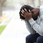 A woman experiencing unrequited love, looking at her phone while sitting at a window.