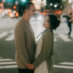 Man and woman standing holding hands on the street on their third date