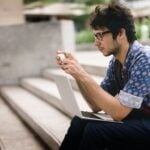 Man sitting on stairs with laptop and cell phone as symbol why ghosters always come back