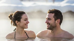A couple looking at each other sitting in hot springs. 