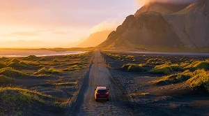 A car driving into the sunset.