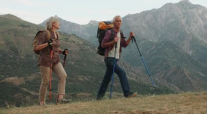 A couple hiking with backpacks and running poles.
