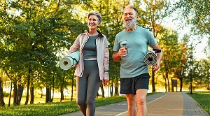 A couple walk the streets with yoga mats under their arms, on their way to an outdoor workout.
