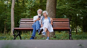 A couple sitting on a bench in a park, chatting.
