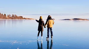 A couple side by side ice skating in the winter.
