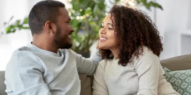 Couple sitting on a couch having a nice conversationg both smiling
